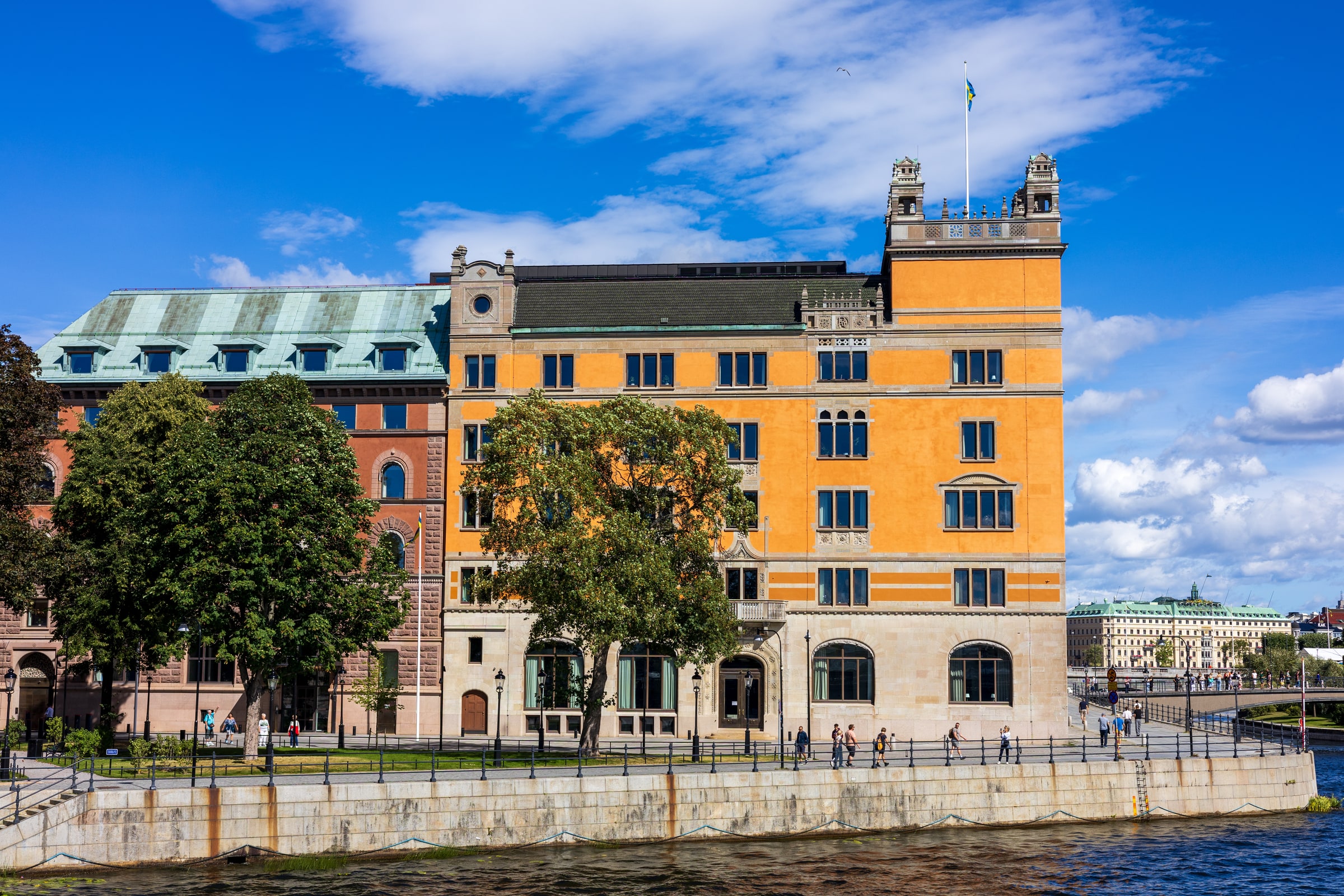 Rosenbad’s orange facade, arched windows and Swedish flag beside the water in Stockholm.