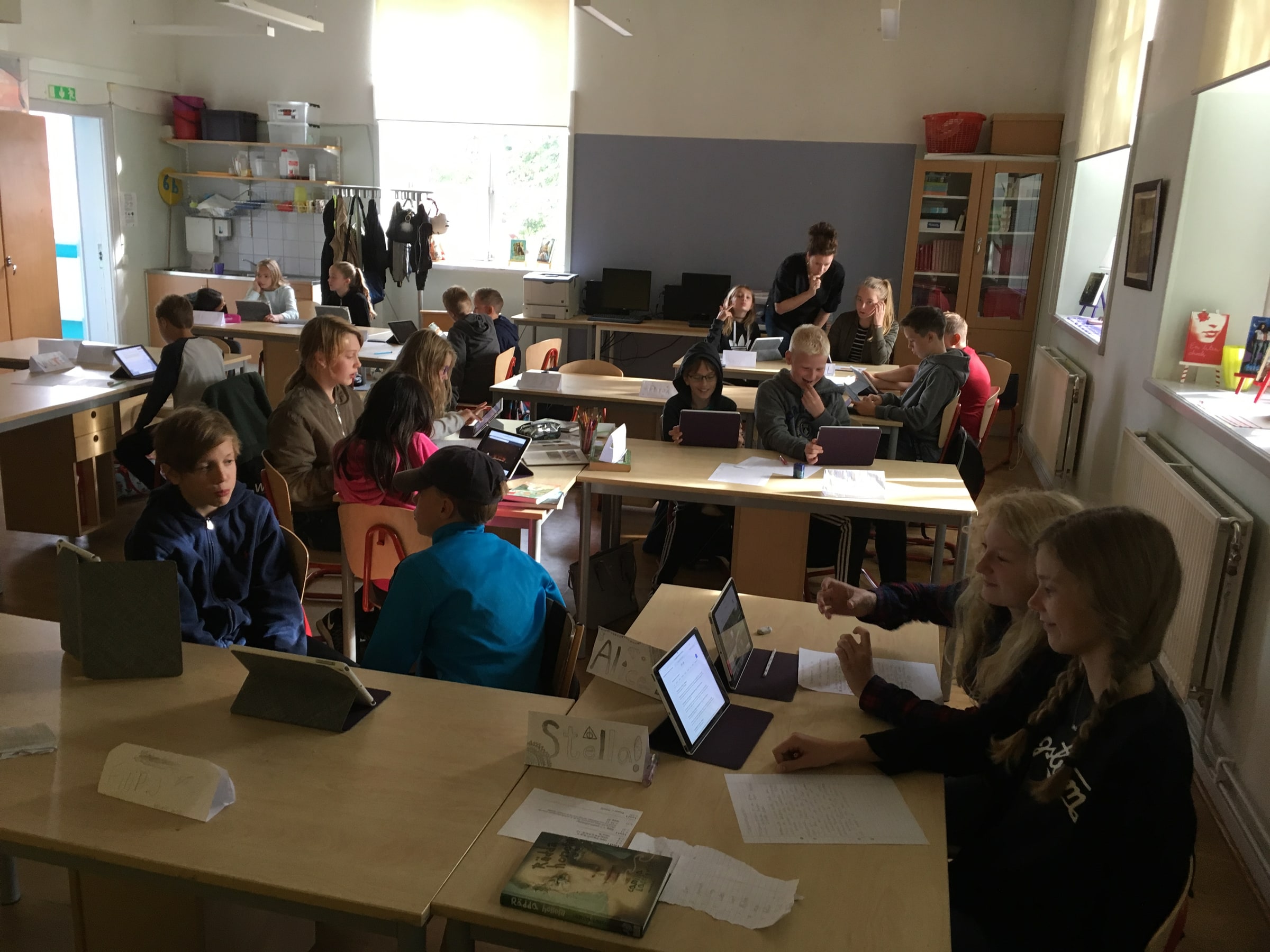 Pupils work at tables while a teacher helps a group in a classroom at Enskede school in Stockholm.