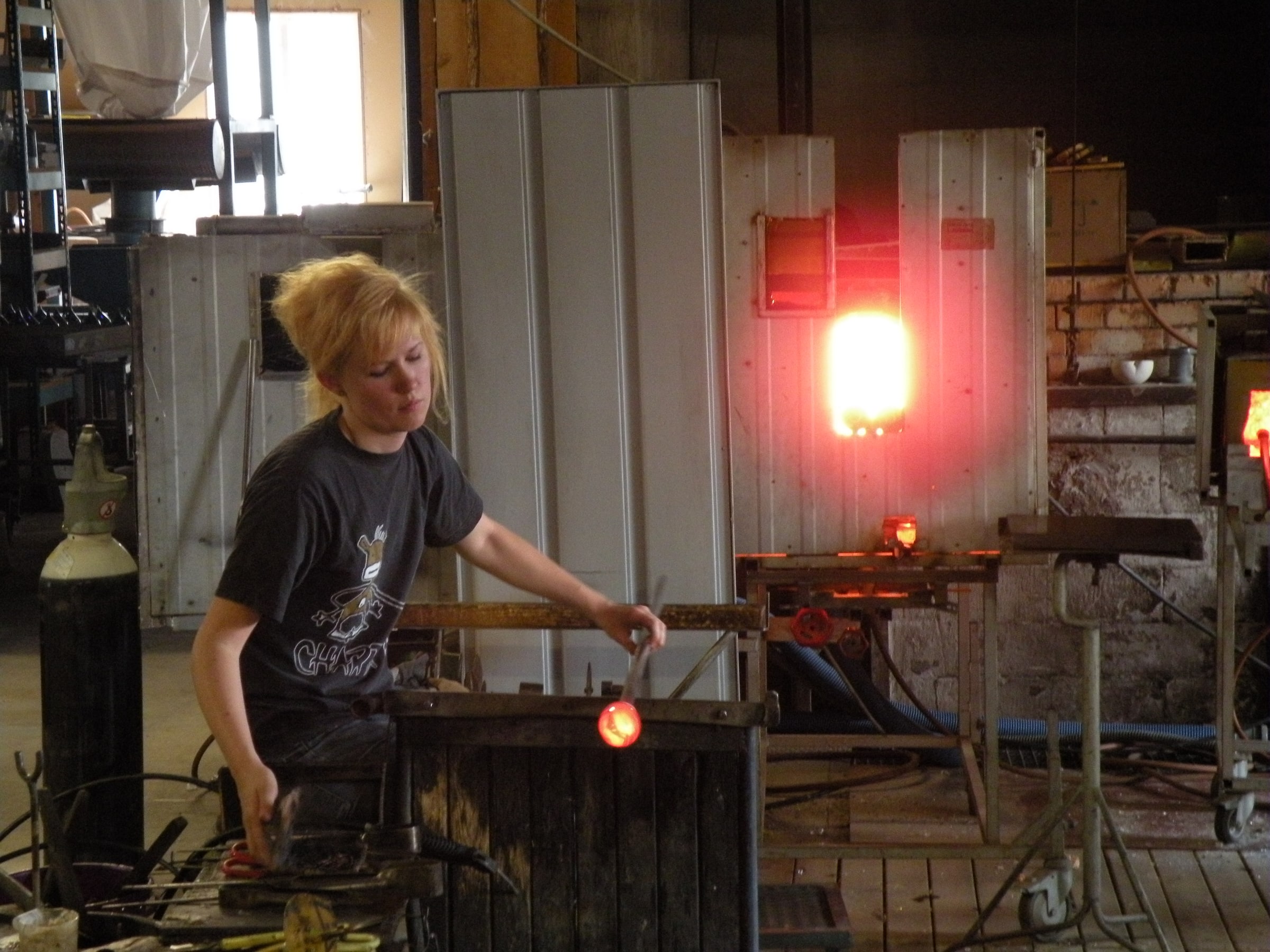 A glassworker handles glowing glass at Bergdala glassworks in Sweden.