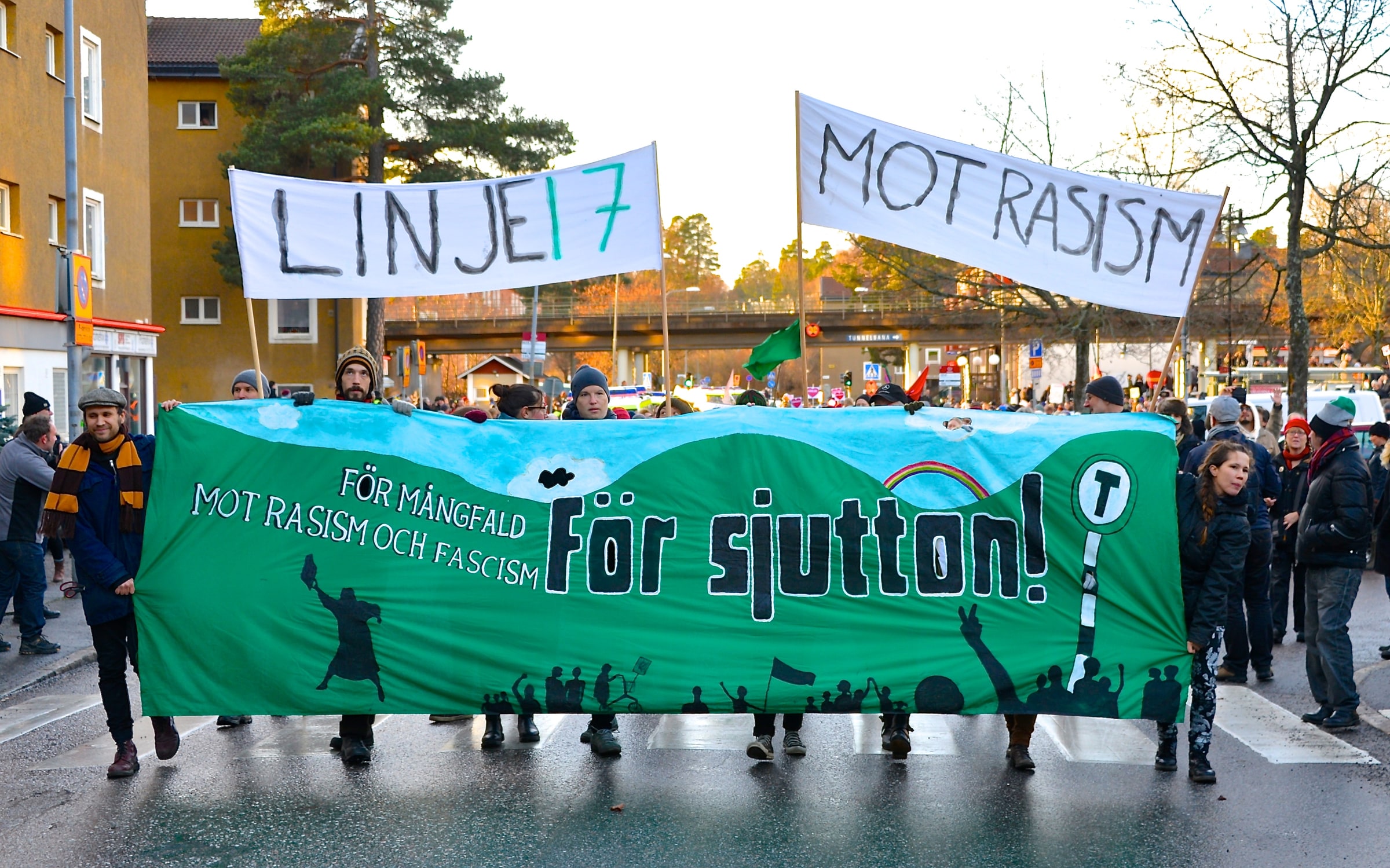 People carry banners reading Linje 17 and Mot rasism at an anti-racism march in Kärrtorp, Stockholm.