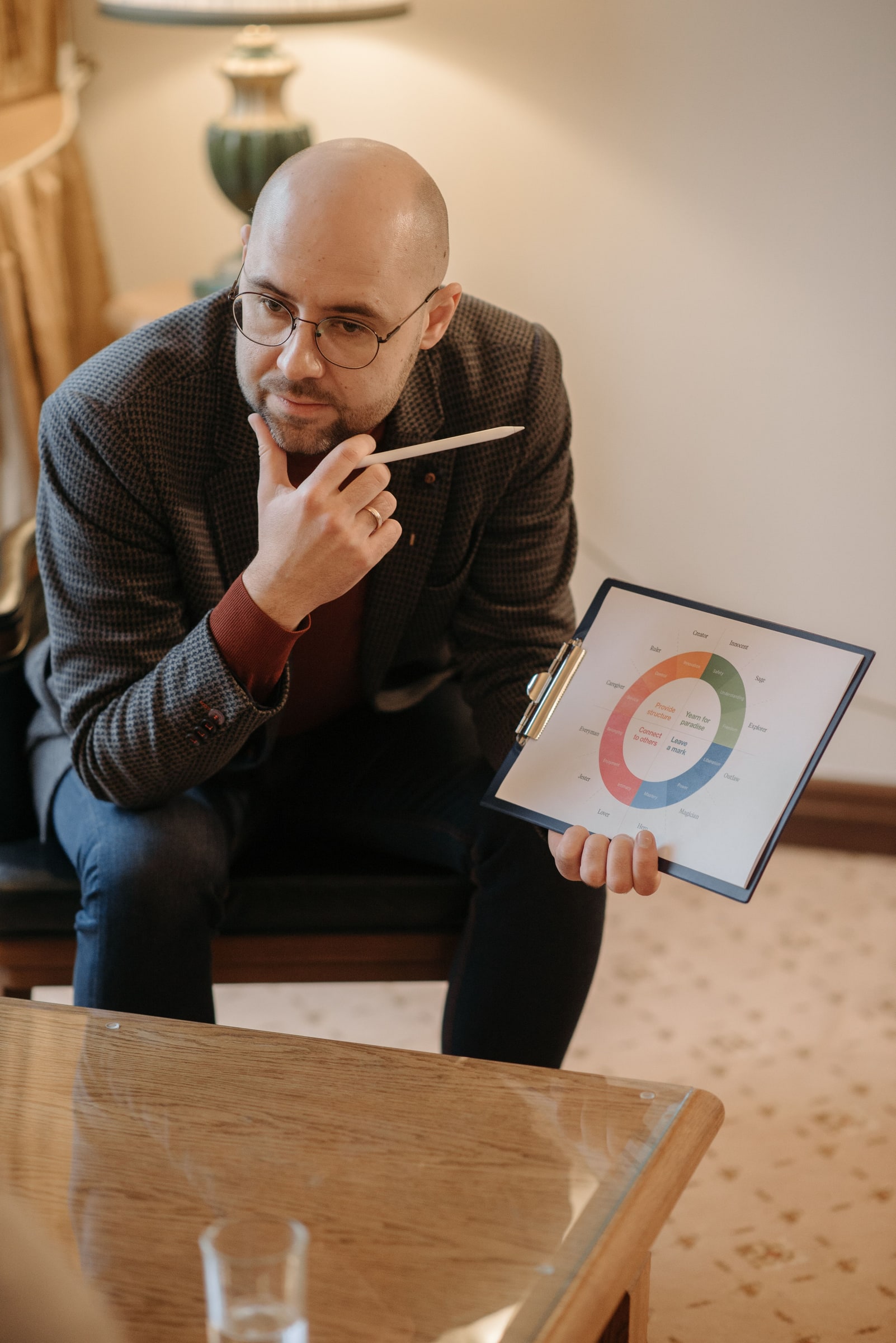 A counsellor holds a circular assessment chart on a clipboard while seated indoors.