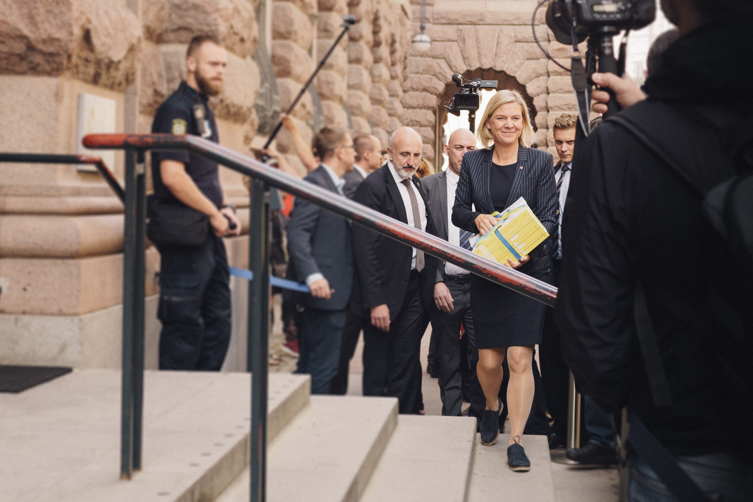 Magdalena Andersson carries Sweden’s budget towards the Riksdag through a crowd of officials and cameras.