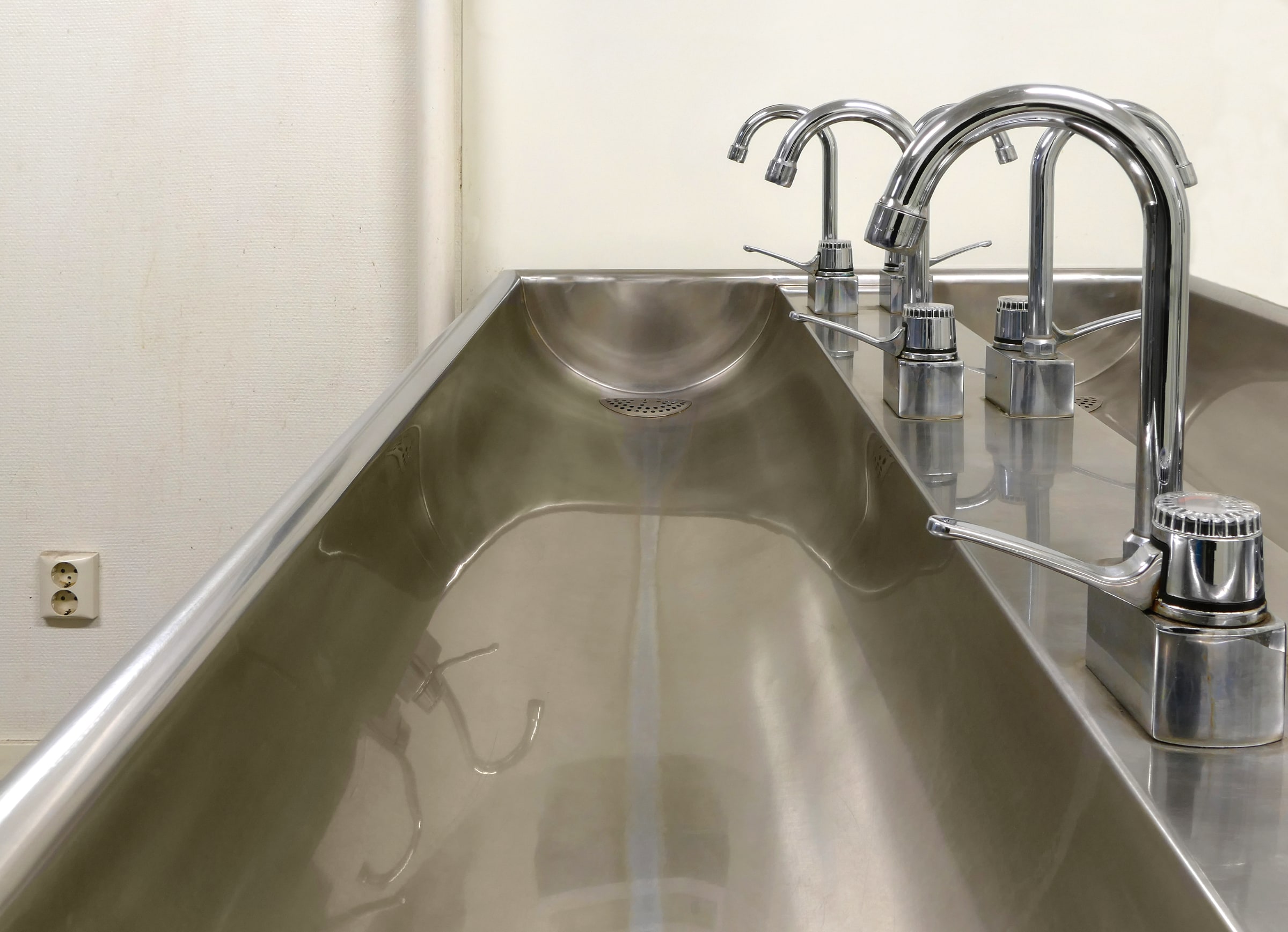 Chrome taps above a stainless-steel washbasin in Gåseberg, Sweden, photographed in January 2017.