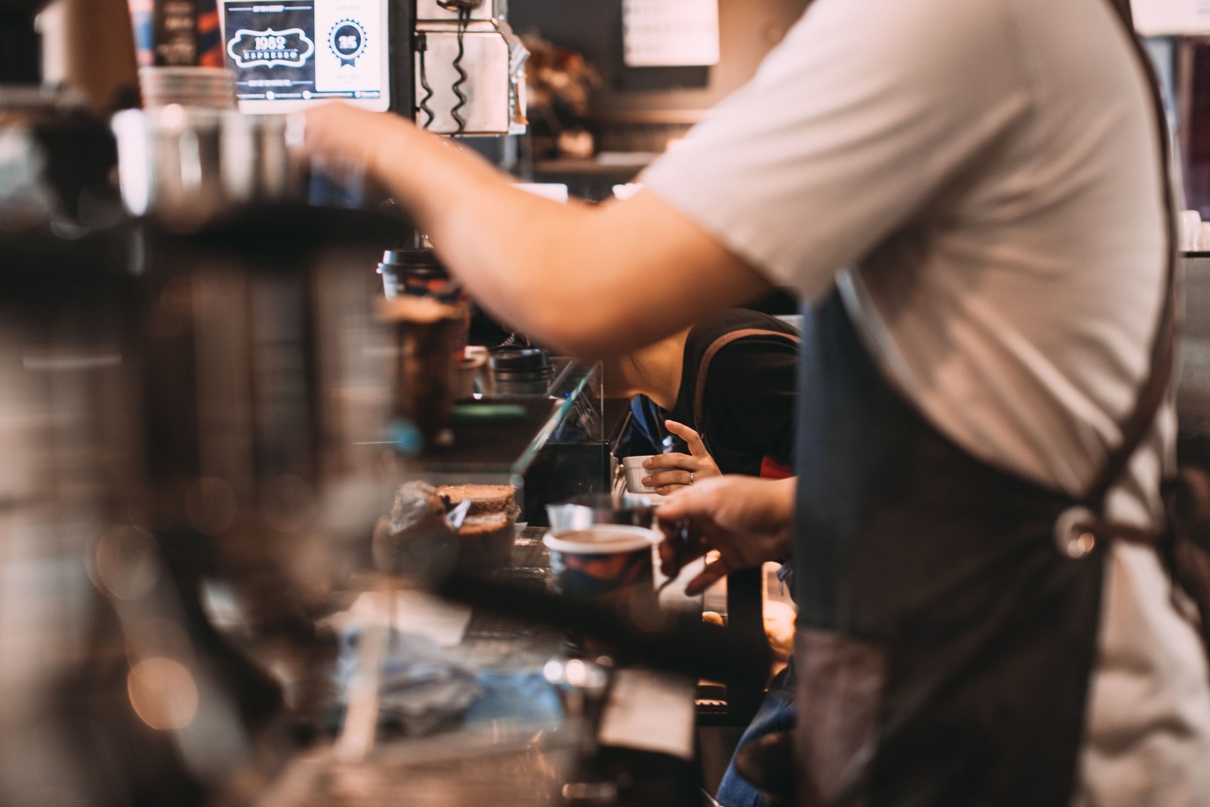 Baristas prepare coffee during a café shift. The photograph is illustrative; the workers are not identified as students, Swedish residents or residence-permit holders.