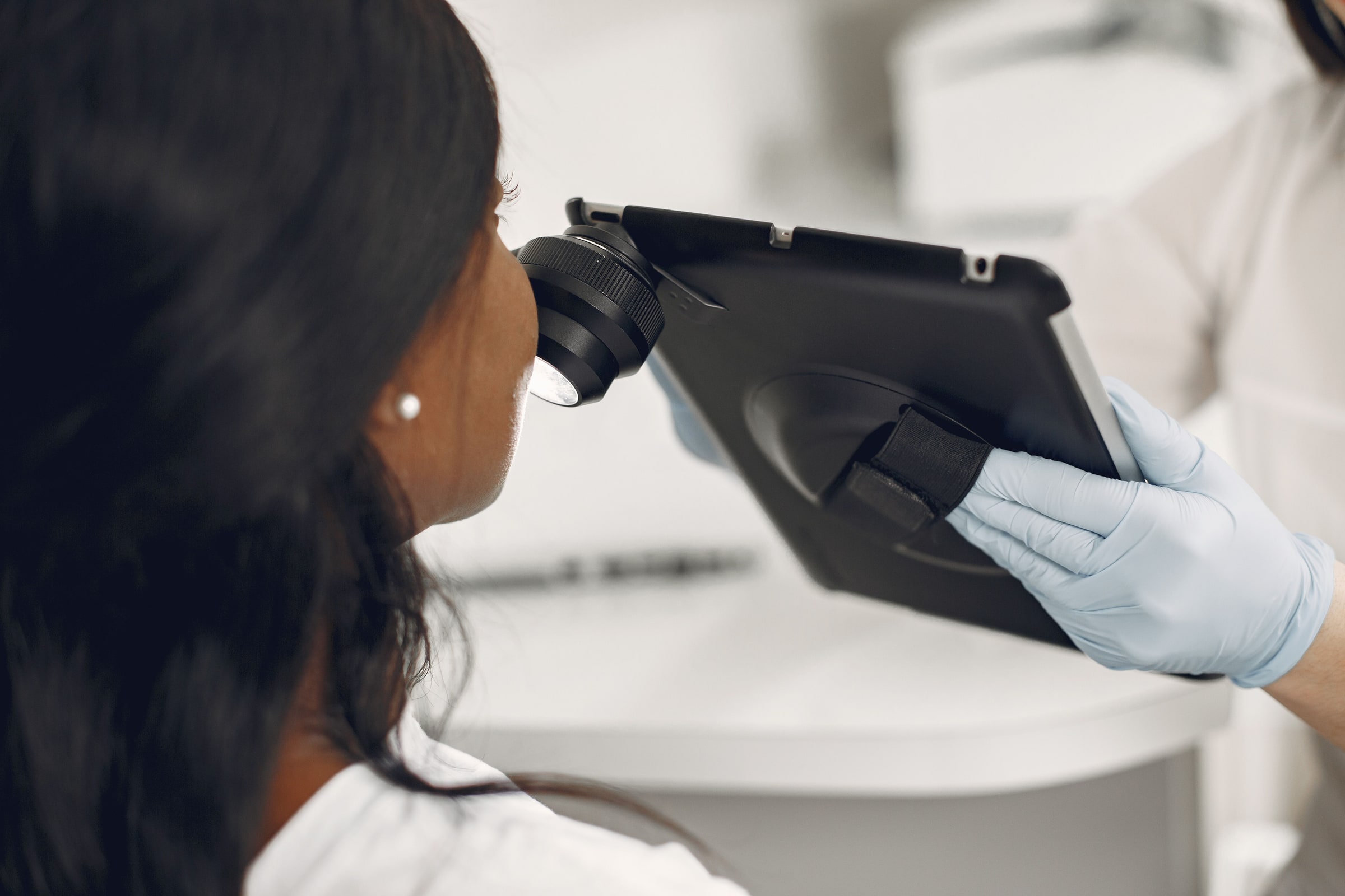 A clinician uses a digital dermatoscope to examine a patient’s skin.